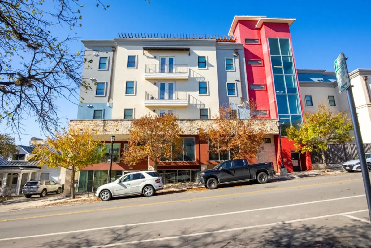 Colorful building with balconies cars trees exterior at Pointe San Marcos in San Marcos Student Accommodation