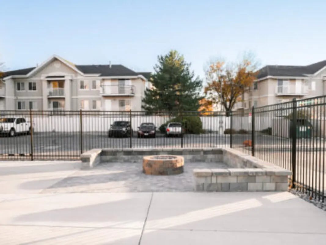 Apartment buildings cars and fire pit area exterior at Village on the Parkway in Orem Student Accommodation