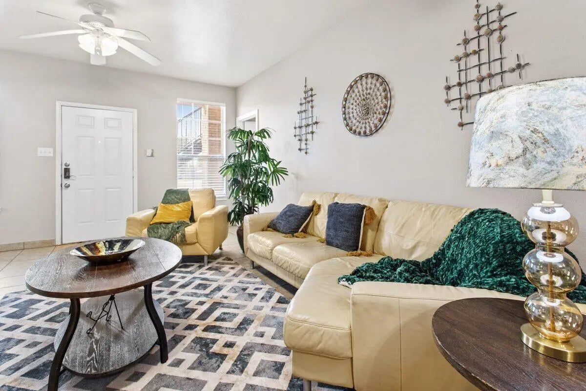 Cream sectional couch plant abstract rug living room at Bear Crossing Apartments in Waco Student Accommodation