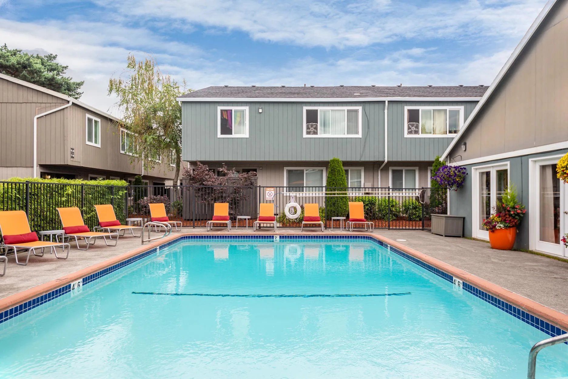 Pool with lounge chairs outside apartment buildings exterior at Connery Place Apartments in Portland Student Accommodation
