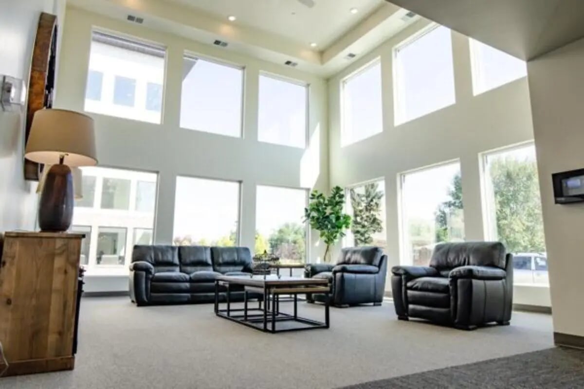 Large windows leather sofas coffee table living area at Sundance Apartments - BYU-Idaho Approved Housing in Rexburg Student Accommodation