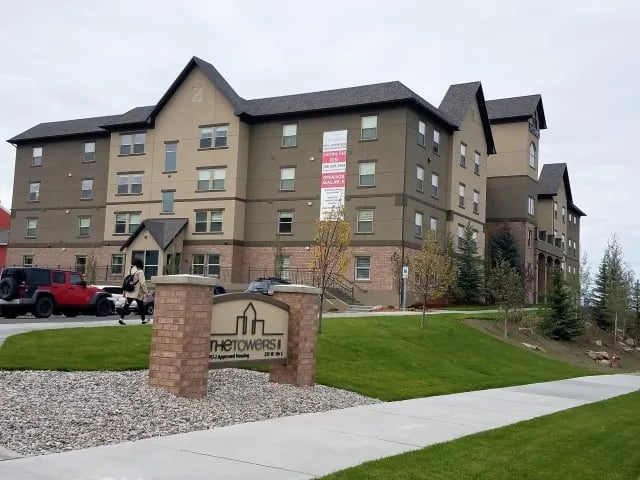 Apartment building sign and vehicles exterior at The Towers Two - Women Approved Housing in Rexburg Student Accommodation