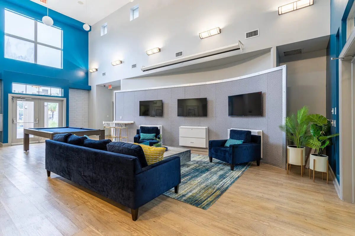 Blue couches pool table televisions and plants lounge area at Hawks Landing in Oxford Student Accommodation
