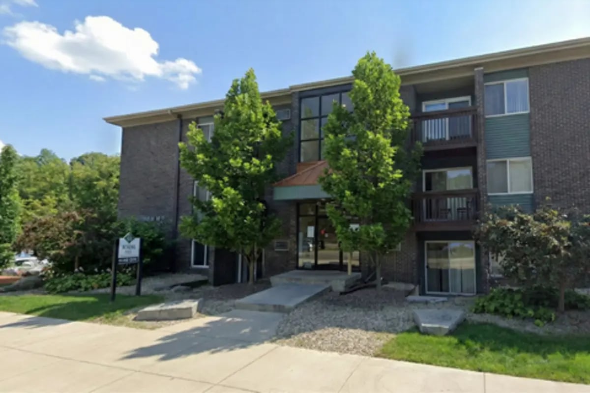 Brick building with balconies and trees exterior at Waters Edge Apartments in East Lansing Student Accommodation