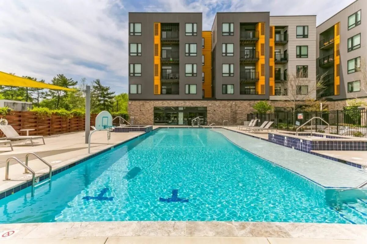 Apartment building with pool basketball hoop lounge chairs exterior at Current Midtown Apartments in Williamsburg Student Accommodation
