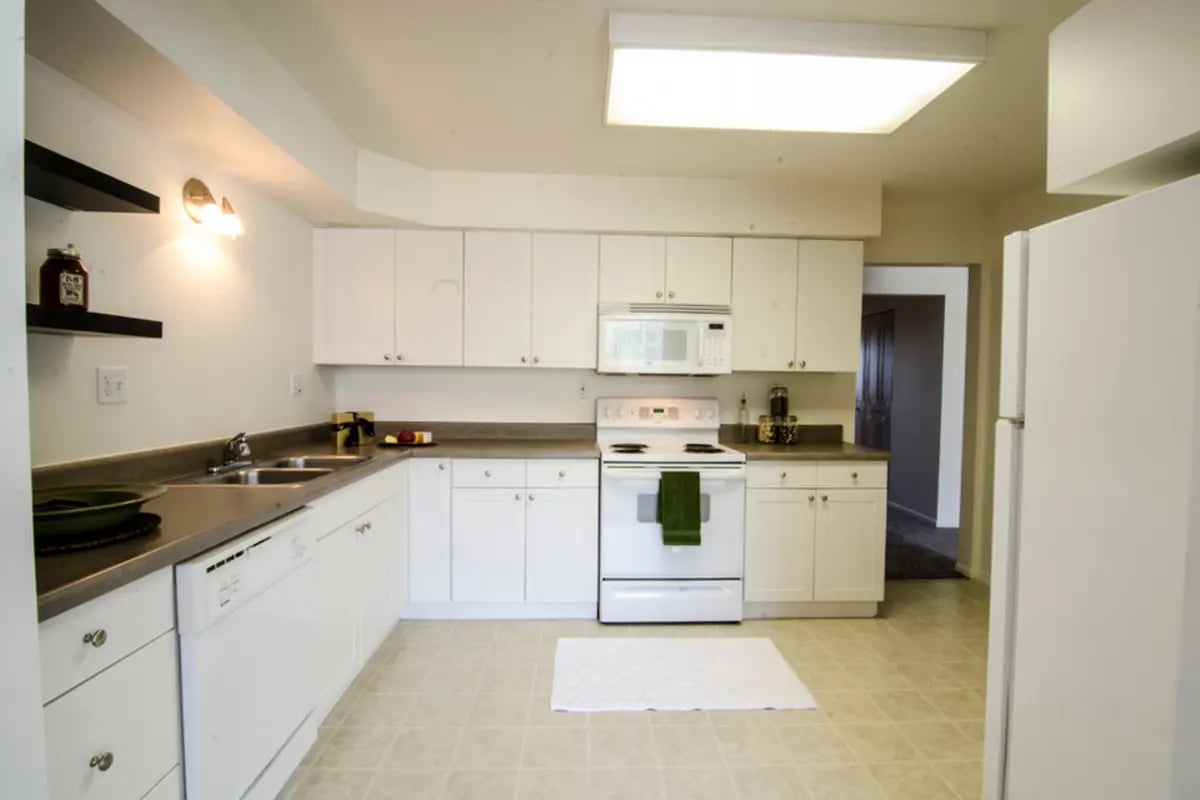 White cabinets microwave stove dishwasher sink kitchen at East Knolls Apartment in East Lansing Student Accommodation