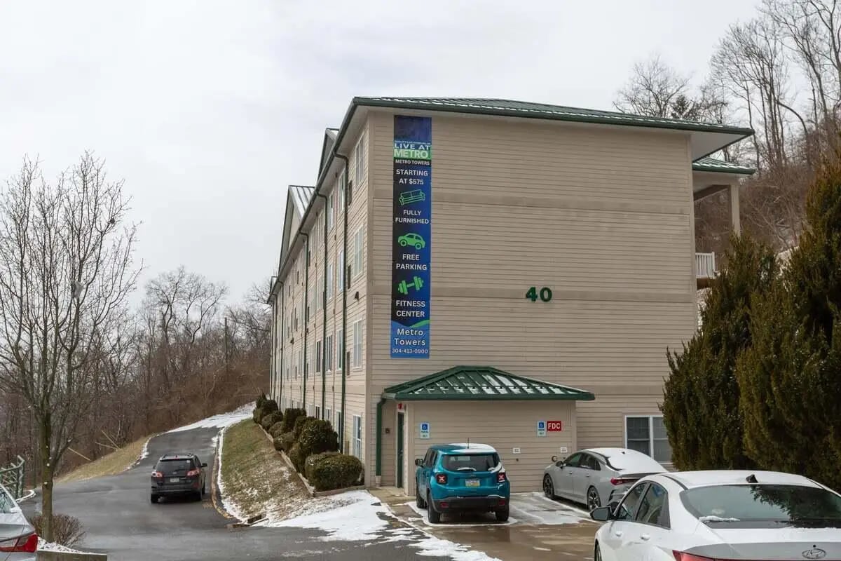 Apartment building with cars in parking lot exterior at Metro Towers in Morgantown Student Accommodation