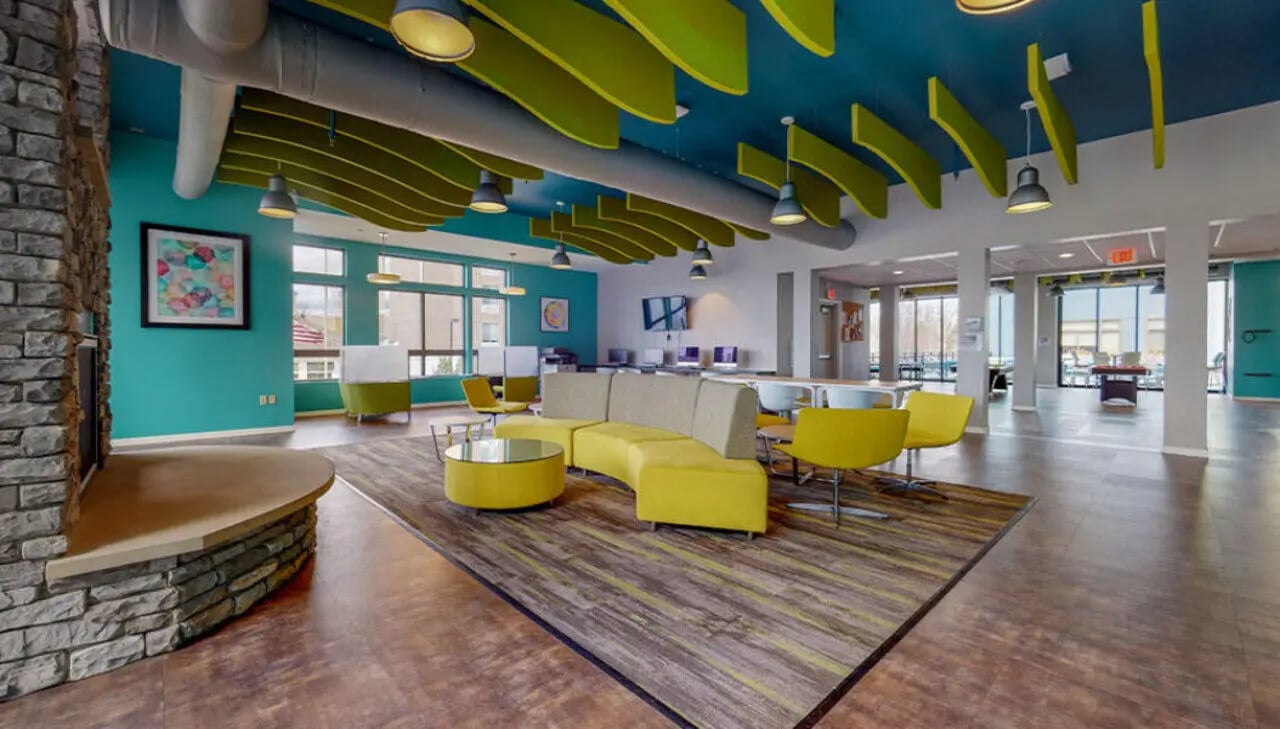 Modern common area with curved yellow sofa and tables at Auden Albany in Albany Student Accommodation
