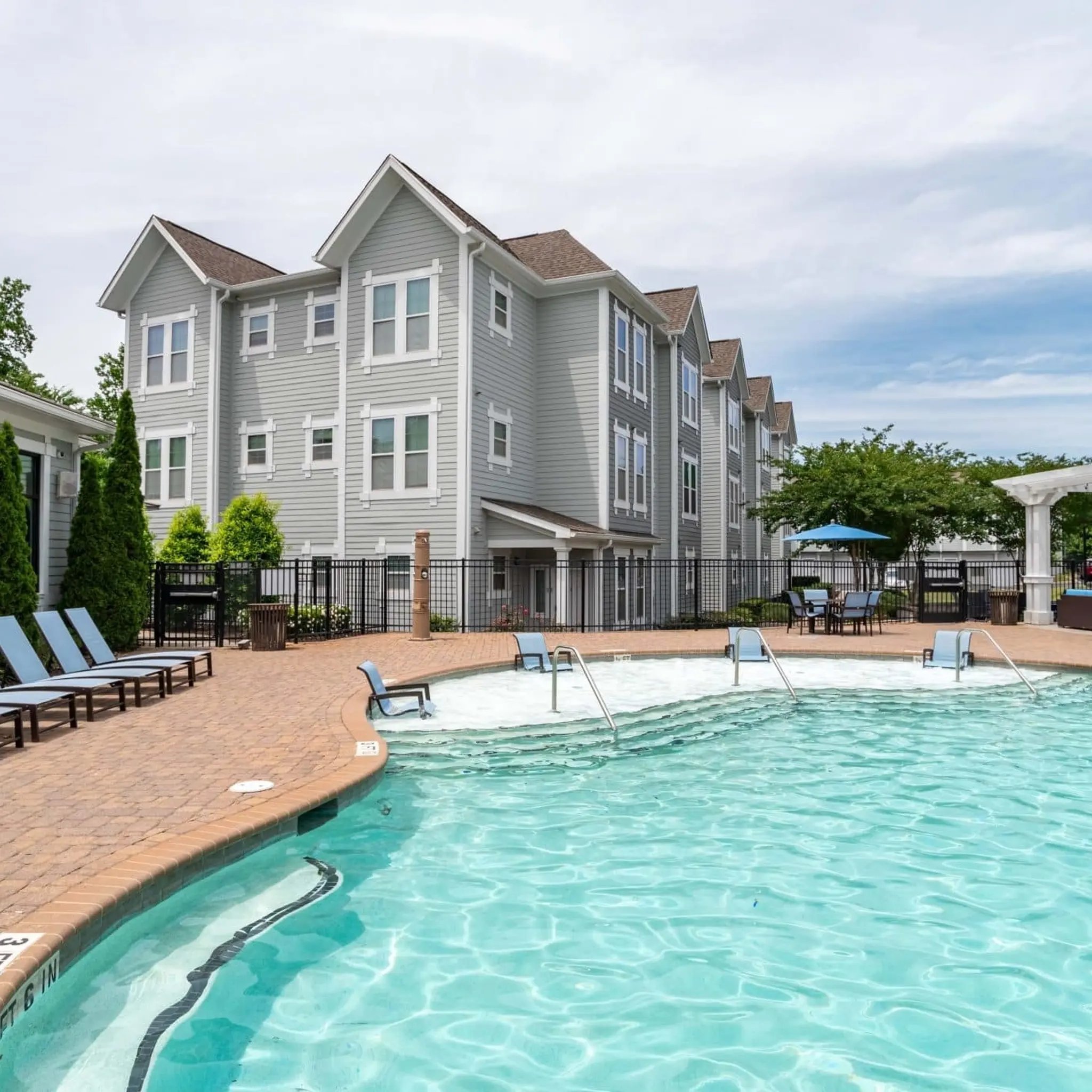 Apartment buildings poolside lounge chairs patio and pool exterior at Millennium One Apartments in Charlotte Student Accommodation