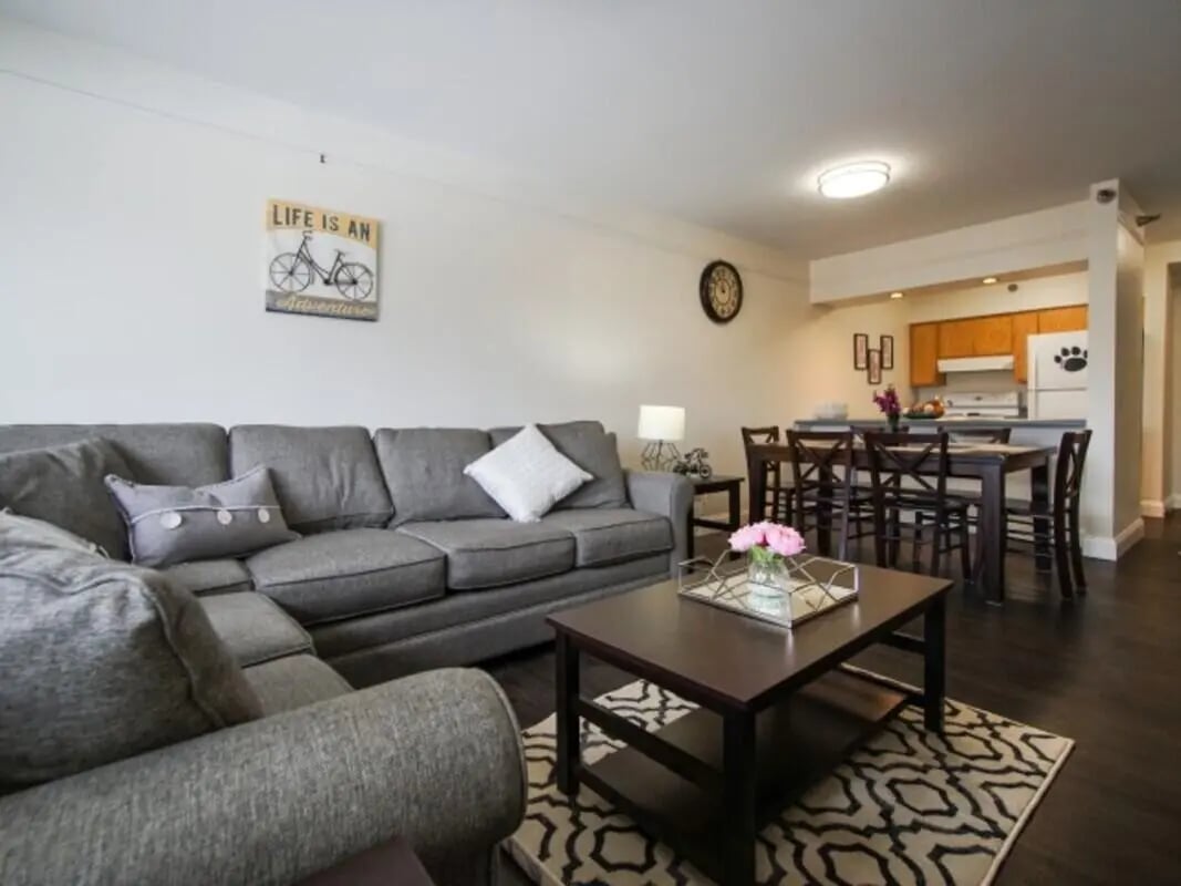Gray sectional sofa coffee table and kitchen living area at Greenwich Court Apartments in State College Student Accommodation