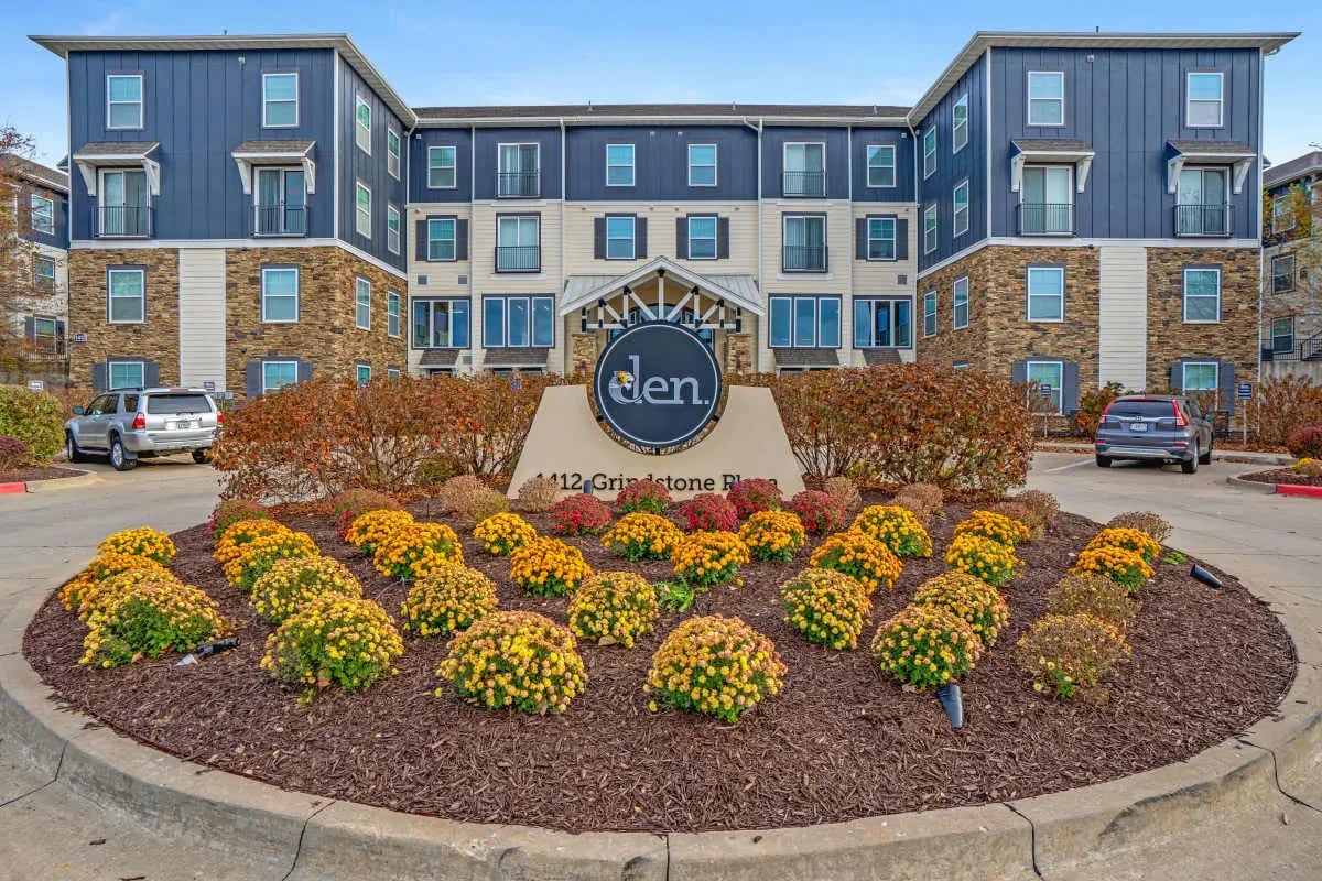 Modern apartment building with sign and flowers exterior at The Den Apartments in Columbia Student Accommodation