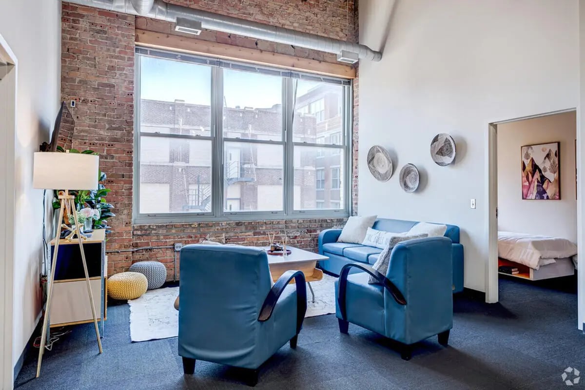 Blue sofa two chairs coffee table and bed living room at The Letterman Chicago Apartments in Chicago Student Accommodation