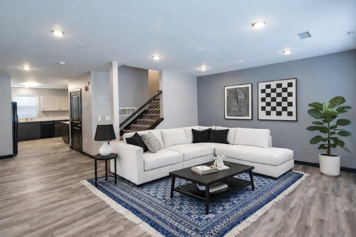 White sectional sofa black coffee table blue rug living room at CitySide By Alexa in Bloomington Student Accommodation