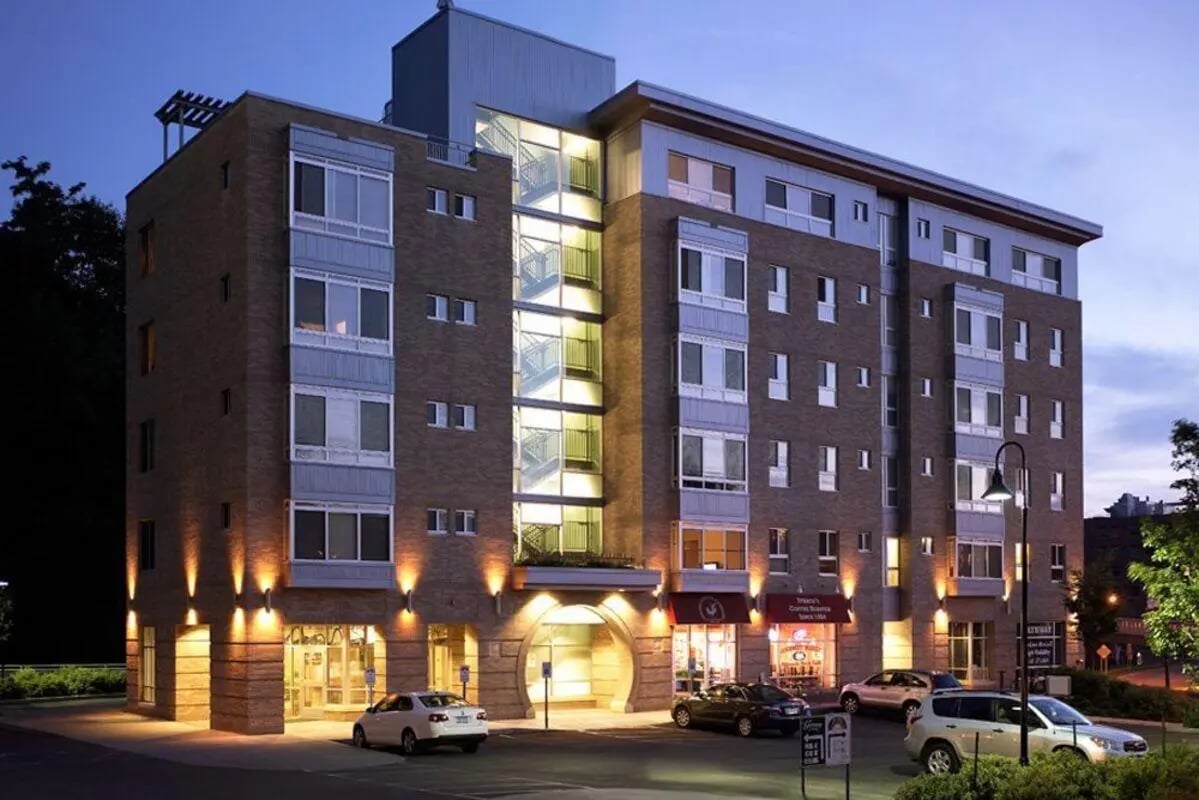 Brick apartment building with cars and storefronts exterior at 407 College Ave in Ithaca Student Accommodation