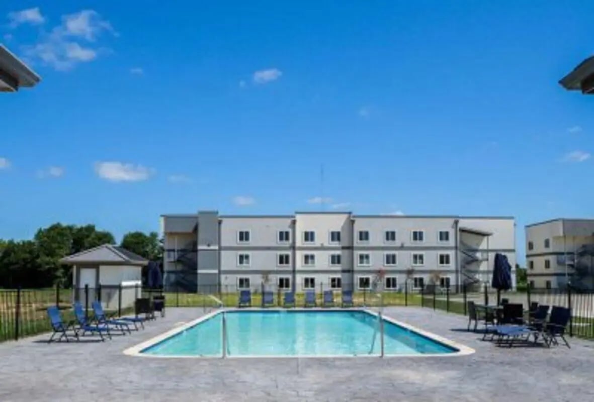 Apartment building with pool lounge chairs exterior at 625 at Prairie View Apartments in Prairie View Student Accommodation