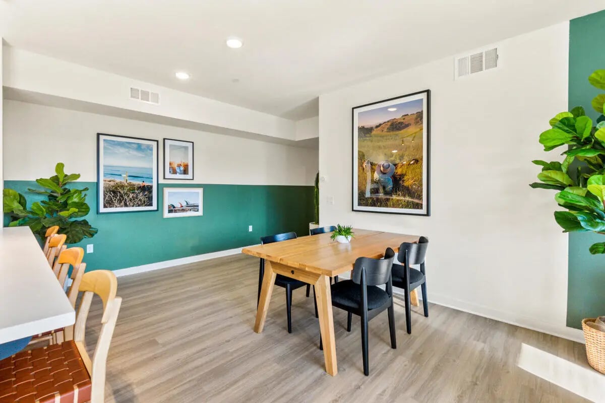 Wooden table with chairs artworks and plants communal area at Ascent at Campus of Life in San Diego Student Accommodation