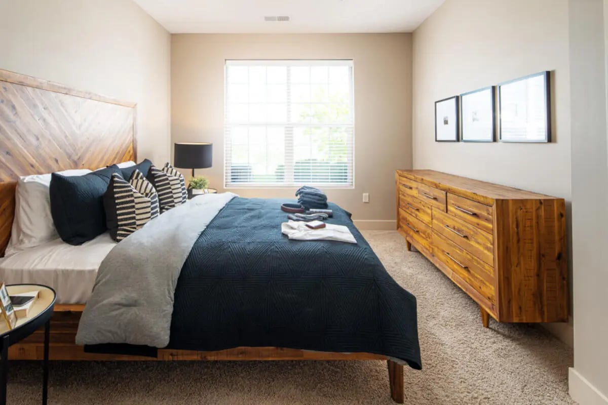 Wooden bed with navy pillows and dresser bedroom at Broadmoor Hills in Omaha Student Accommodation