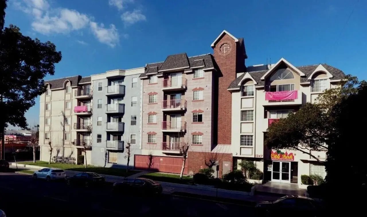 Apartment building with balconies and a clock tower exterior at City Park Apartments in Los Angeles Student Accommodation