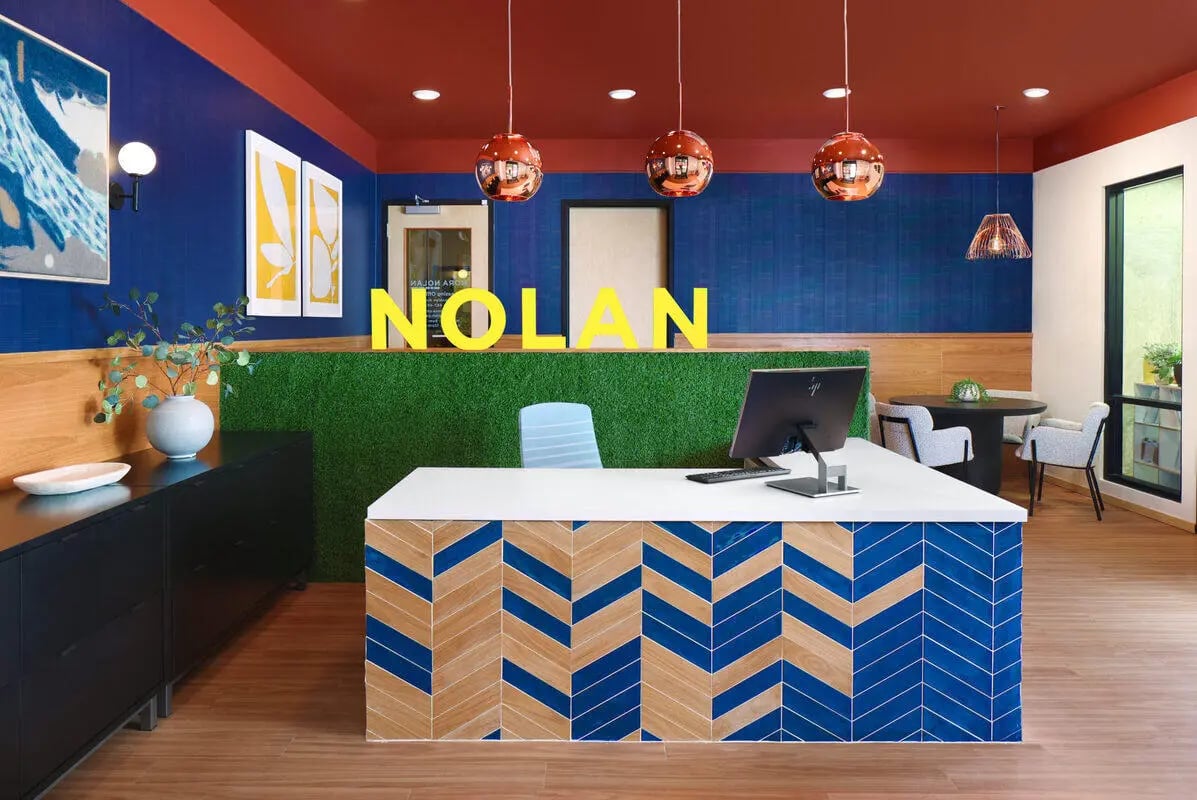 Reception desk with monitor grass wall Nolan signage reception area at NOLAN Apartments in Seattle Student Accommodation