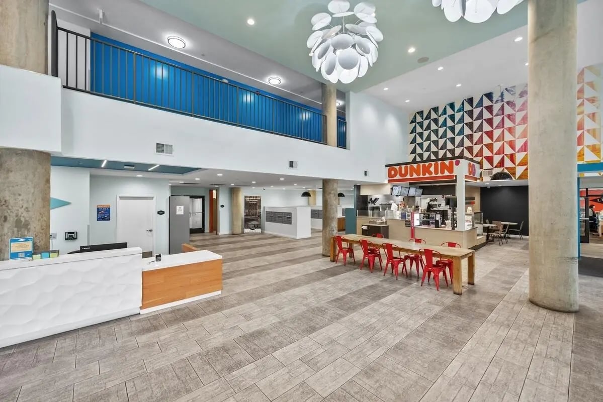 Dunkin area with tables chairs and reception desk common area at Landmark Apartments in College Park Student Accommodation