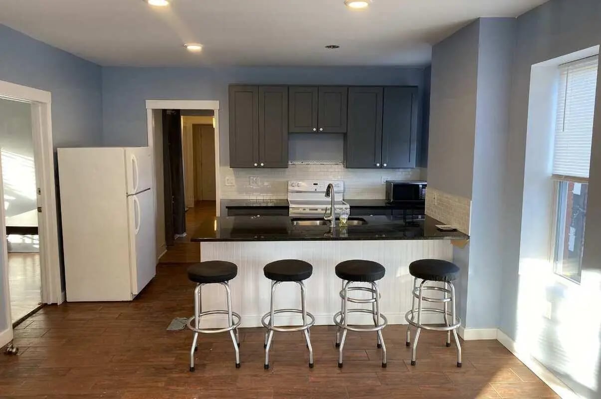 Refrigerator, bar stools, dark cabinets, sink, stove, kitchen at Colonnade Rentals in Oneonta Student Accommodation