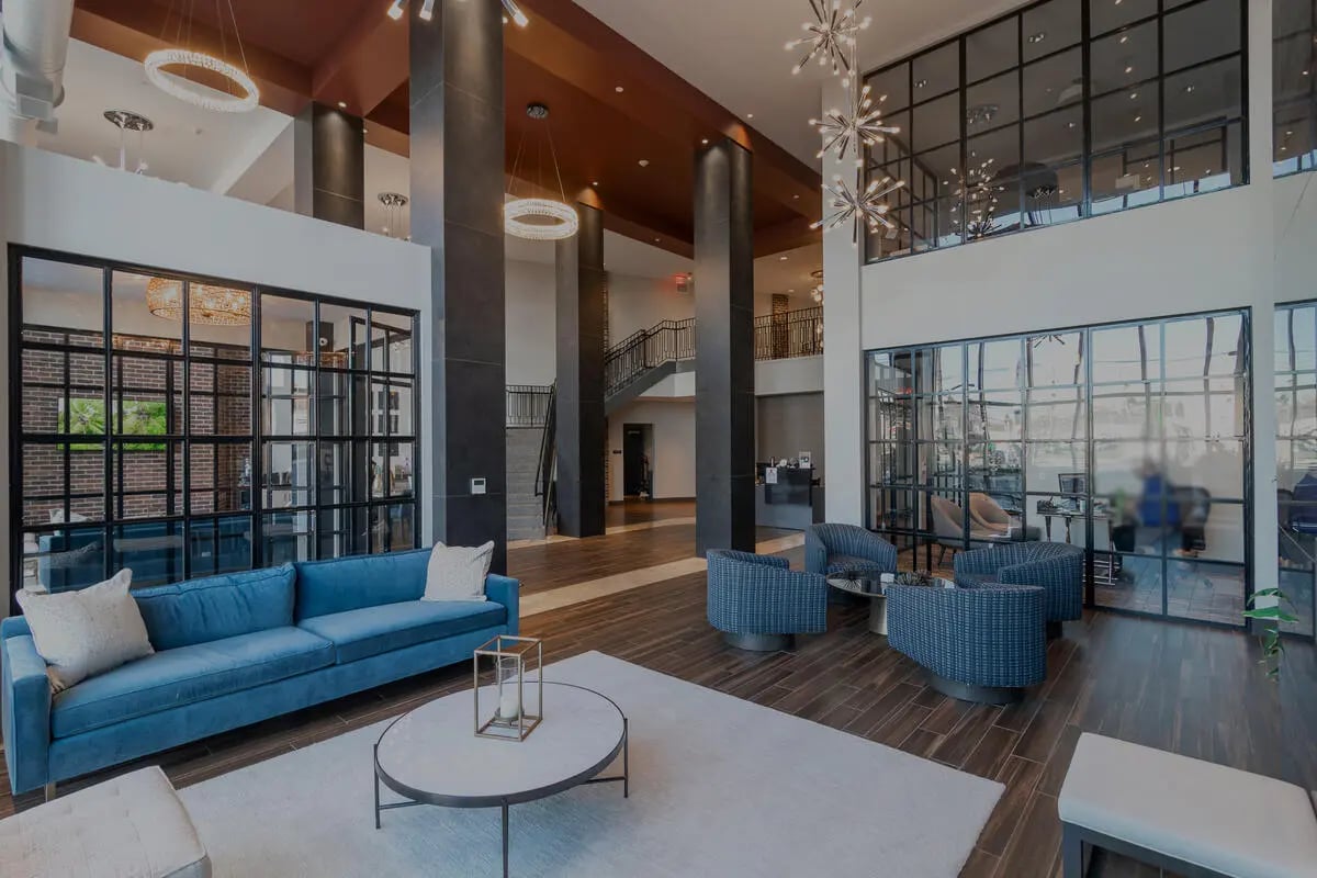 Blue sofa chairs modern chandelier common area living room at 58 E. Main St. Apartments in Newark Student Accommodation