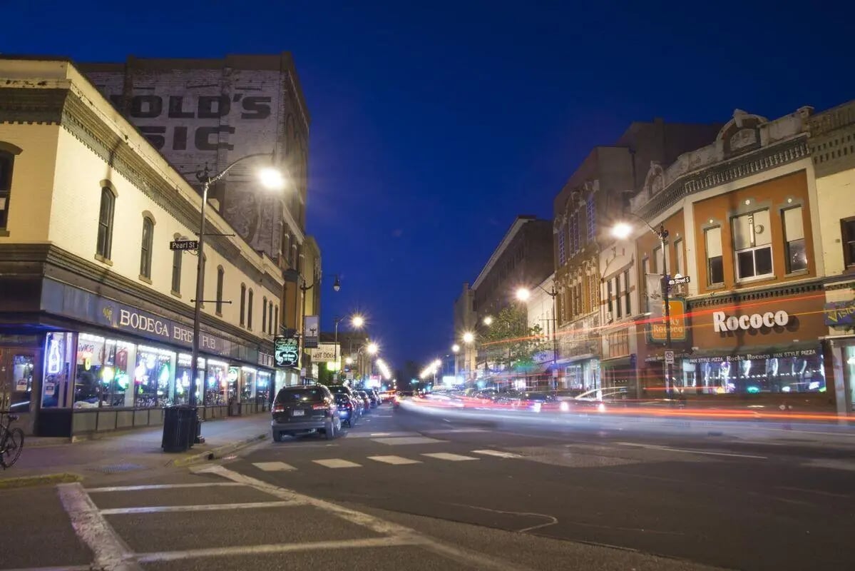 Street with shops and cars at night exterior at Benson Management, Inc. in La Crosse Student Accommodation
