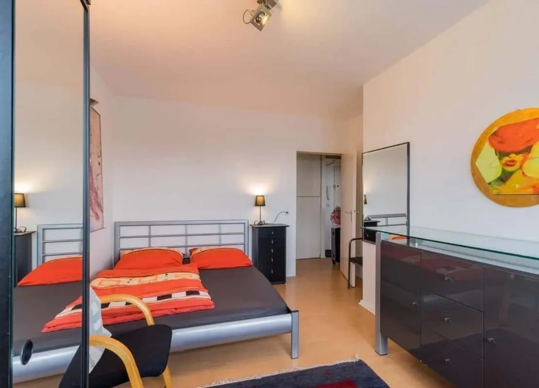 Two beds orange bedding black dresser large mirror bedroom at Apartment in Kurfürstenstraße, 10785 Berlin, Germany in Berlin Student Accommodation