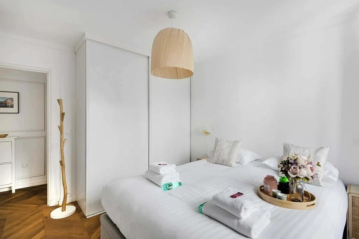 Bed with towels a vase and wooden hanger Bedroom at Apartment in 30 Rue de Saintonge, 75003 Paris, France in Paris Student Accommodation