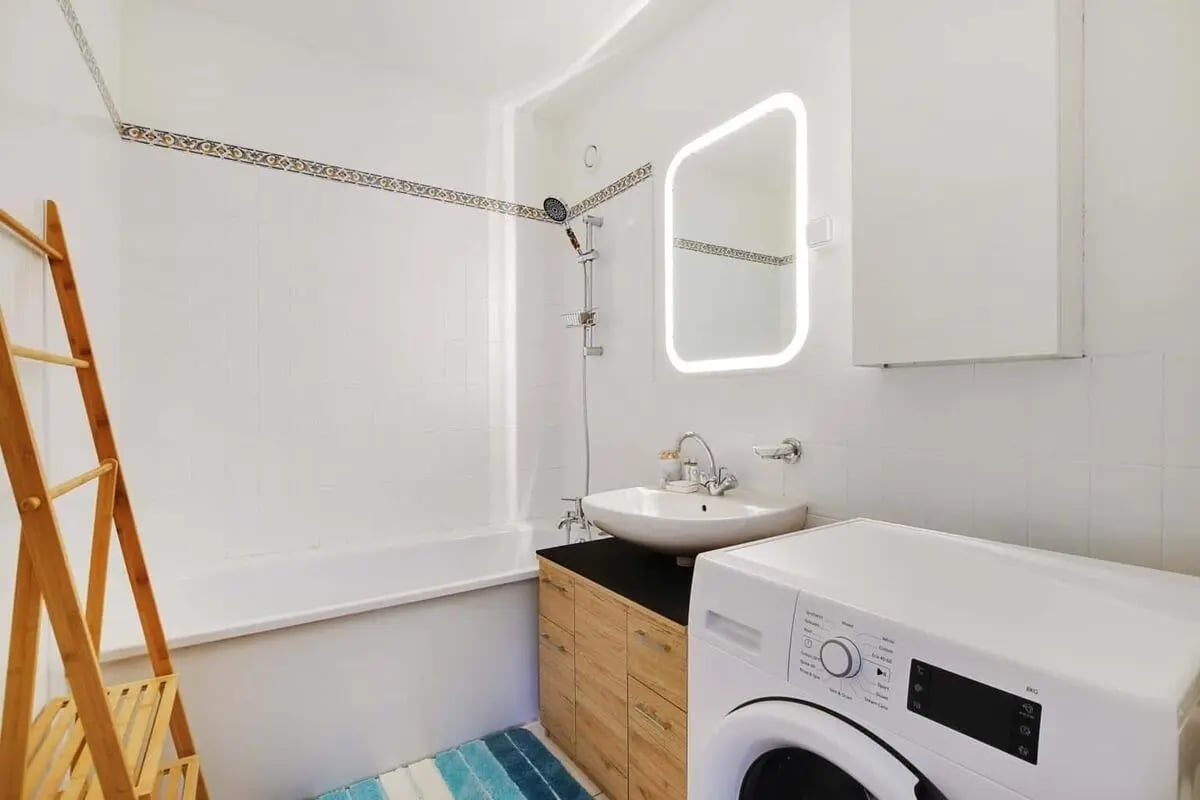 Bathtub sink mirror and washing machine bathroom at Apartment in 85 Rue de l'Ourcq, 75019 Paris, France in Paris Student Accommodation
