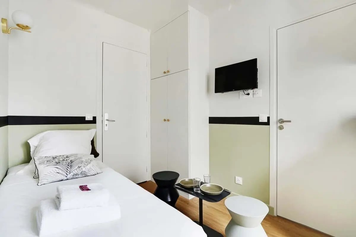 Bed towels television cabinets and doors bedroom at Studio in 103 Rue Brancion, 75015 Paris, France in Paris Student Accommodation