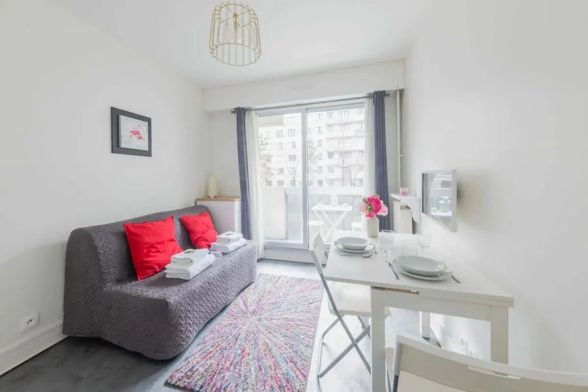 Sofa red pillows folded towels rug dining table living room at Studio in 11 Rue de Thionville, 75019 Paris, France in Paris Student Accommodation