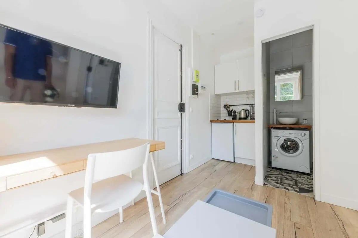 Wall mounted TV wooden desk white chair small kitchen bathroom Bathroom at Studio in 107 Rue des Dames, 75017 Paris, France in Paris Student Accommodation