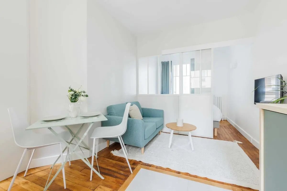 Blue sofa white chairs mint table white rug living area at Studio in 4 Rue de Nantes, 75019 Paris, France in Paris Student Accommodation