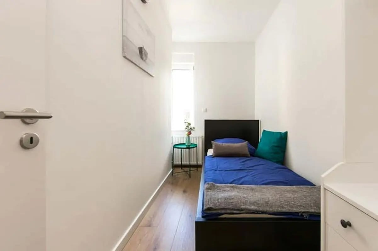Bed with blue bedding and small table bedroom at Room in Elßholzstraße, 10781 Berlin-Bezirk Tempelhof-Schöneberg, Germany in Berlin Student Accommodation