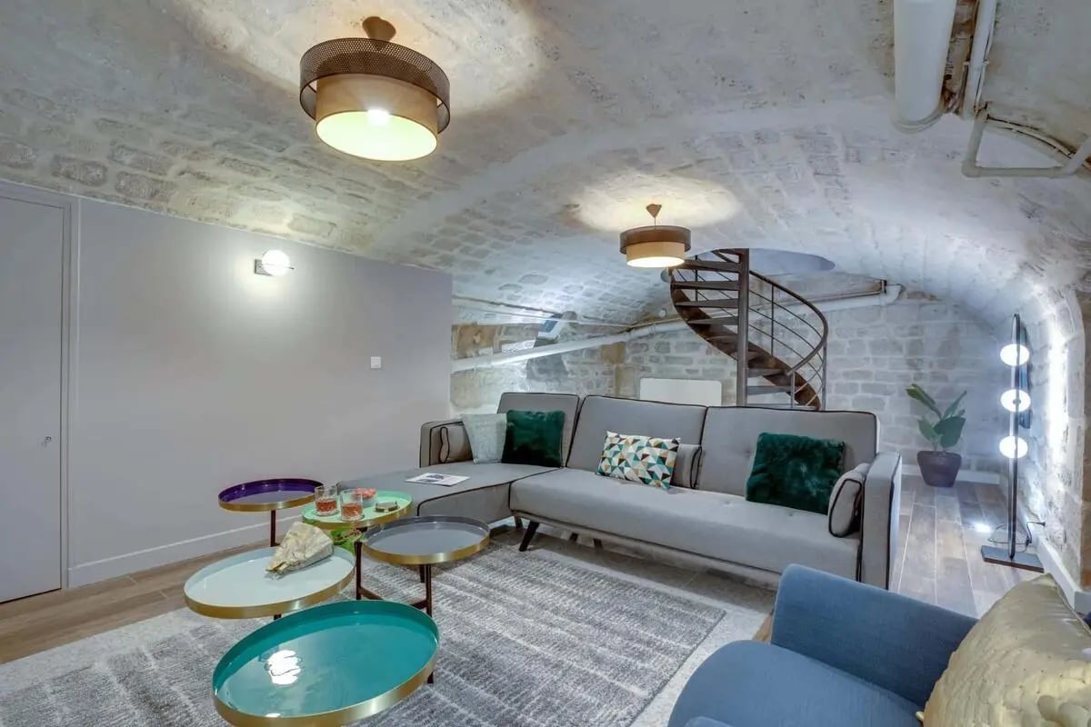 Grey sectional sofa colorful tables spiral staircase living room at Apartment in 4 Cité de Trévise, 75009 Paris, France in Paris Student Accommodation