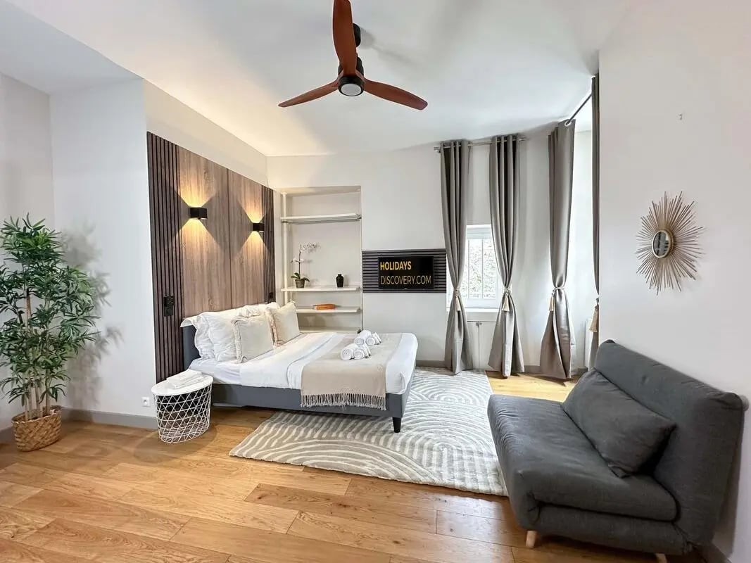 Bed with side table couch and fan Bedroom at Studio in 15 Rue de Lille, 75007 Paris, France in Paris Student Accommodation