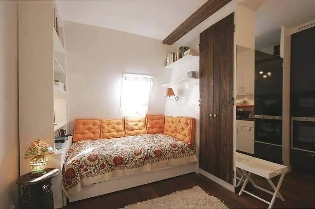 Daybed with orange cushions and patterned bedding living room at Studio in 24 Rue Dauphine, 75006 Paris, France in Paris Student Accommodation