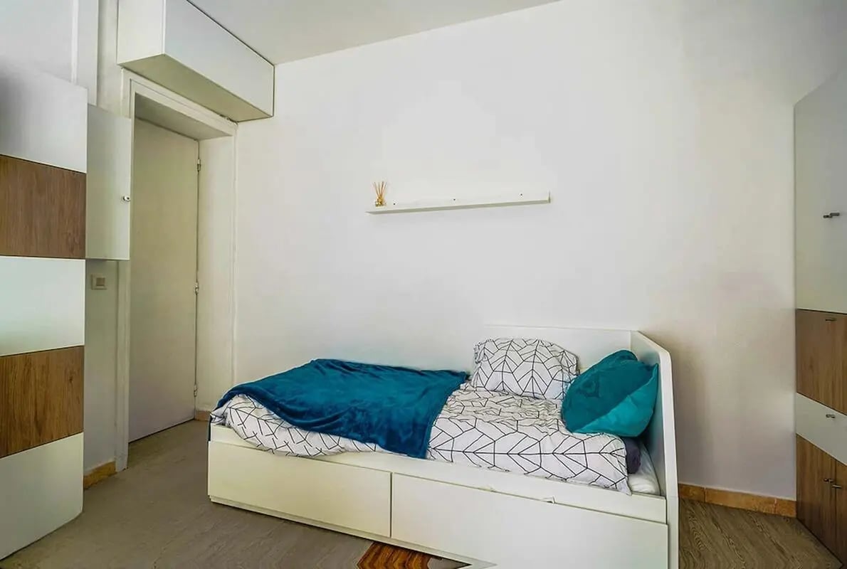 Bed with teal throw and patterned bedding bedroom at Studio in Rue Jean Maridor, 75015 Paris, France in Paris Student Accommodation