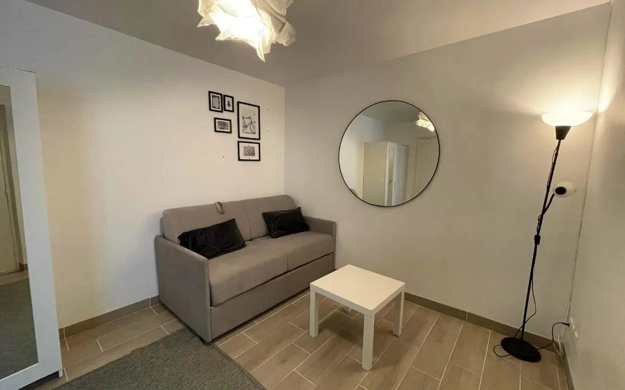 Sofa table mirror framed art and floor lamp living room at Studio in Rue des Dames, 75017 Paris, France in Paris Student Accommodation