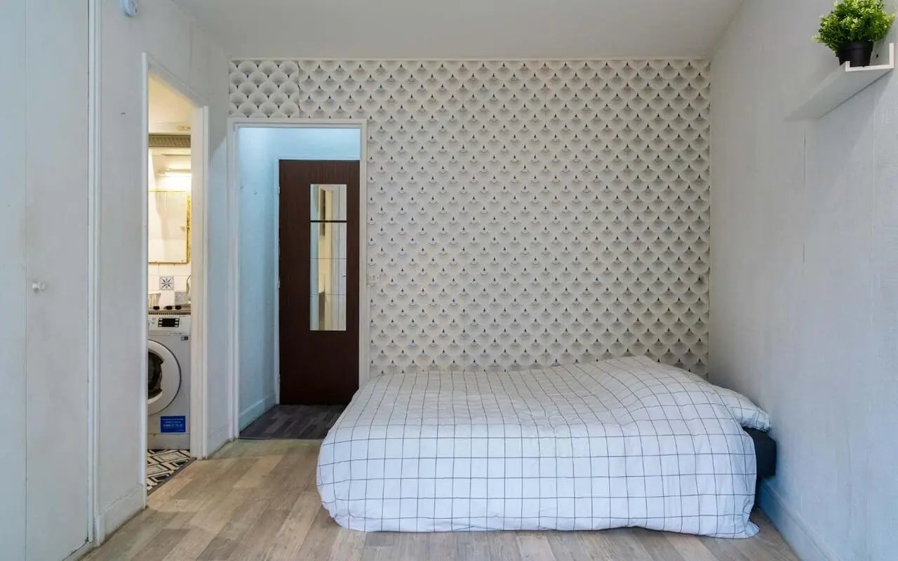 Bed with patterned wallpaper and washing machine bedroom at Studio in Rue Marx Dormoy, 75018 Paris, France in Paris Student Accommodation