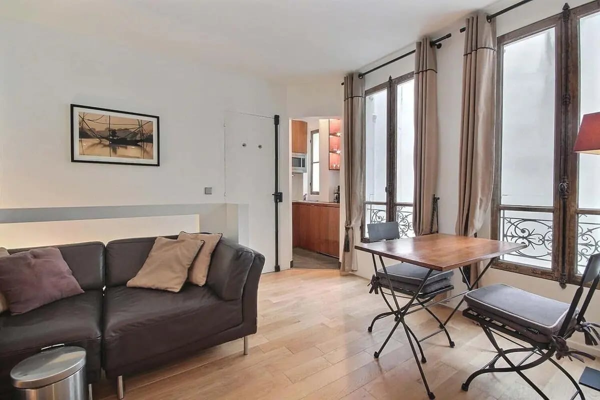 Dark leather couch dining table near windows living room at Apartment in Rue de Seine, 75006 Paris, France in Paris Student Accommodation