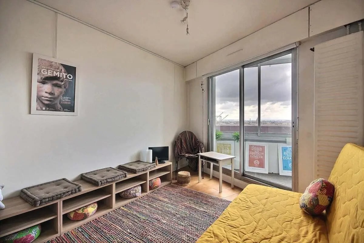 Shelves cushions rug television chair small table yellow sofa living room at Studio in Av. d'Italie, 75013 Paris, France in Paris Student Accommodation