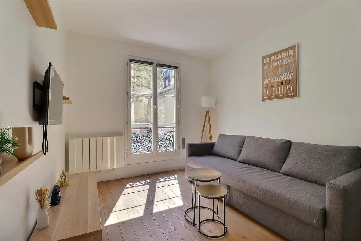 Grey sofa nesting tables radiator TV living room at Apartment in Rue Eugène Varlin, 75010 Paris, France in Paris Student Accommodation