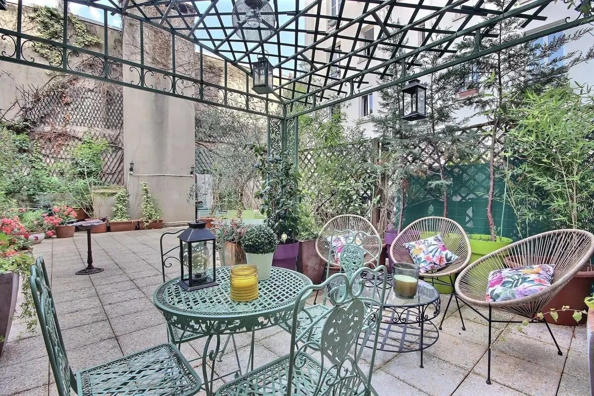 Patio with chairs table plants and lanterns patio at Apartment in Rue Jean Nicot, 75007 Paris, France in Paris Student Accommodation