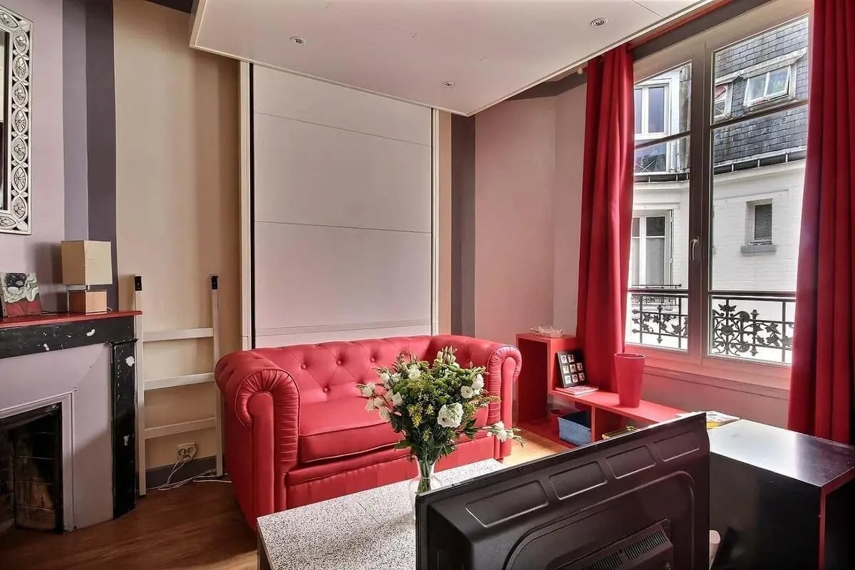 Red sofa fireplace mirror television living room at Studio in Rue de l'Amiral Roussin, 75015 Paris, France in Paris Student Accommodation
