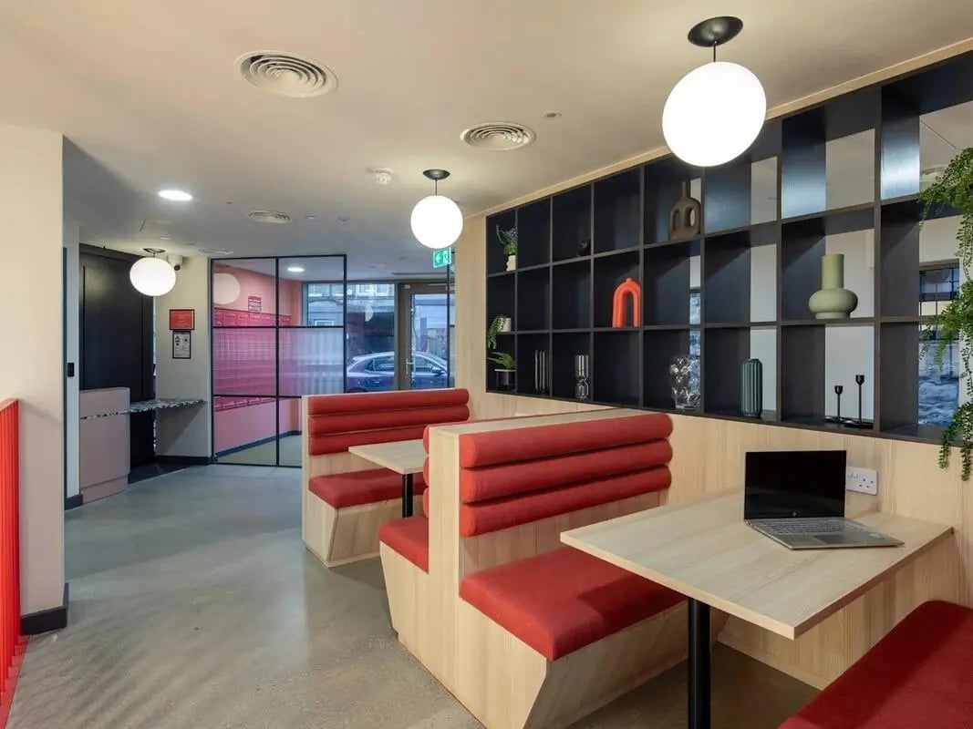 Red booths, tables, shelves, laptop. Common area. at Norton's Student Living in Edinburgh Student Accommodation