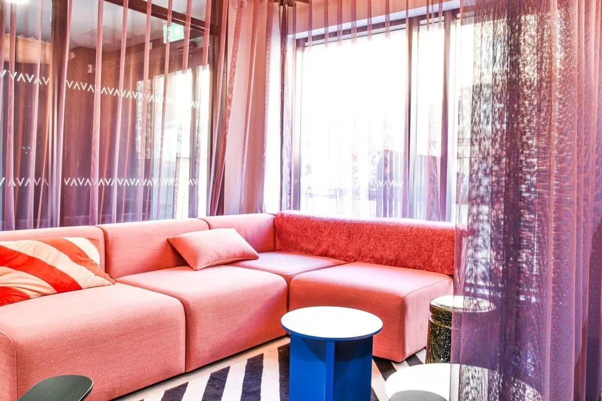 Pink sectional sofa striped pillows two tables living room at Vita Student Iona Street in Edinburgh Student Accommodation