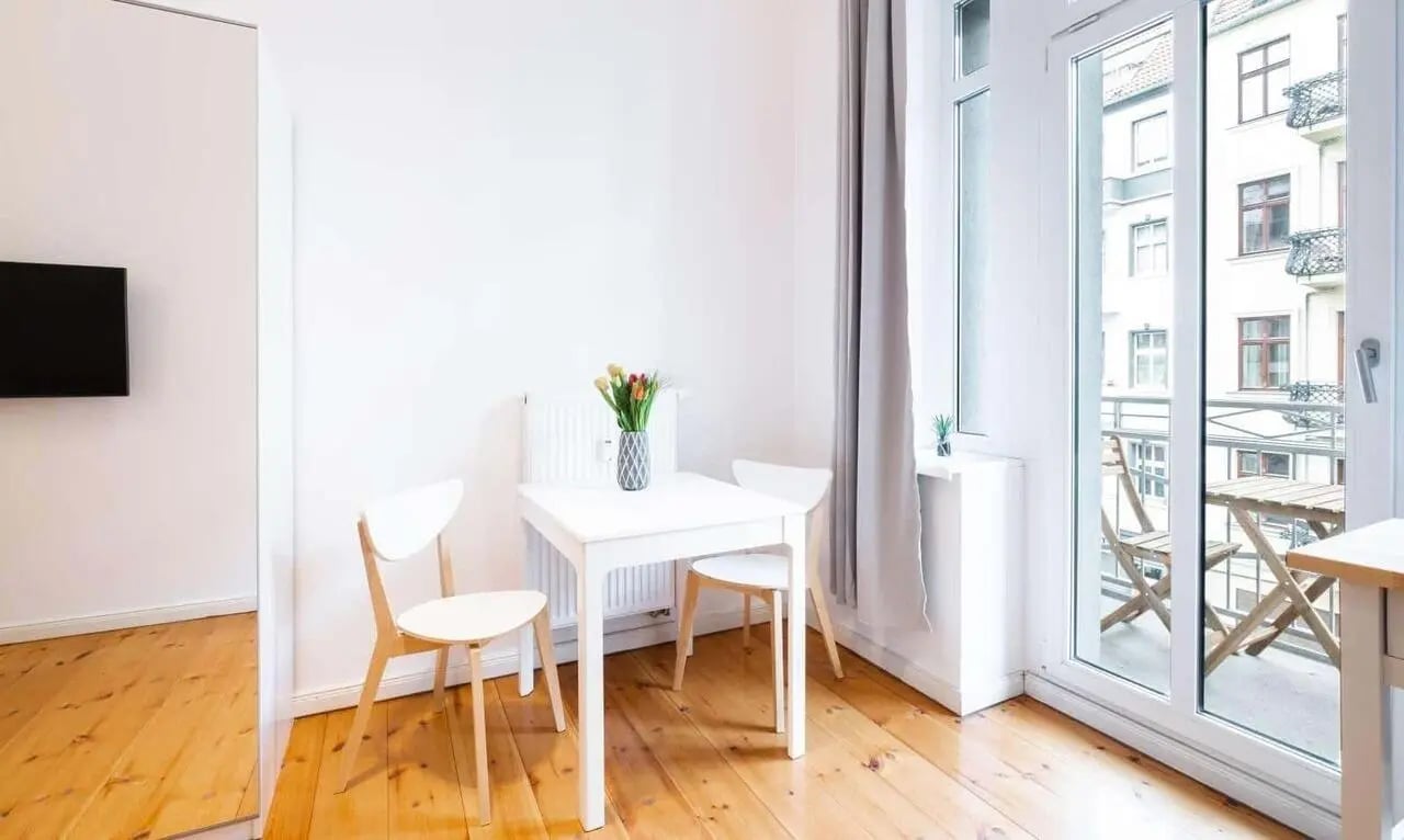 White table two chairs vase flowers television area dining area at Studio for rent in Berlin in Berlin Student Accommodation