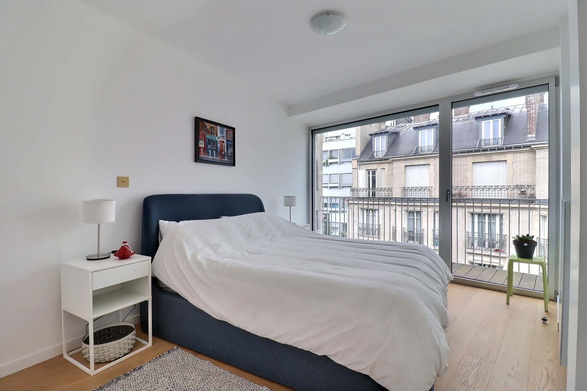 Bed nightstand picture large window overlooking buildings bedroom at Apartment in Rue Damrémont, 75018 Paris, France in Paris Student Accommodation